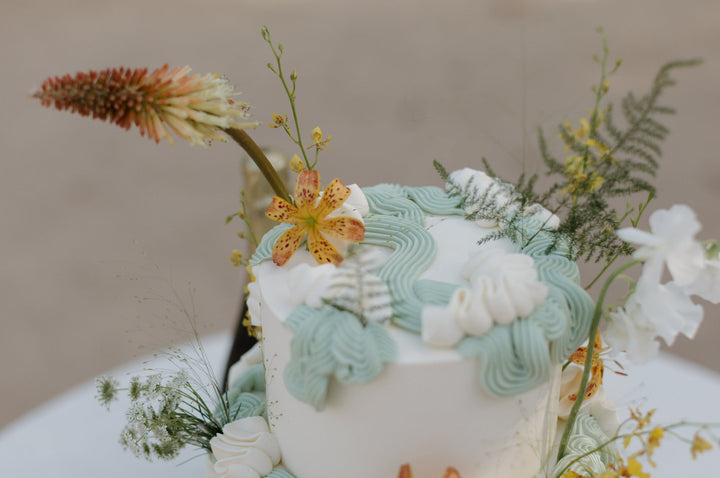 two tiered cake + dessert spread with mini tartlets and tea cakes